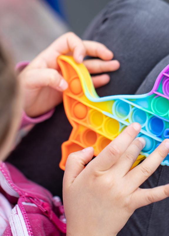 Popular colorful anti-stress touch toy dragon shaped fidgets push pop it in the hands of a child.